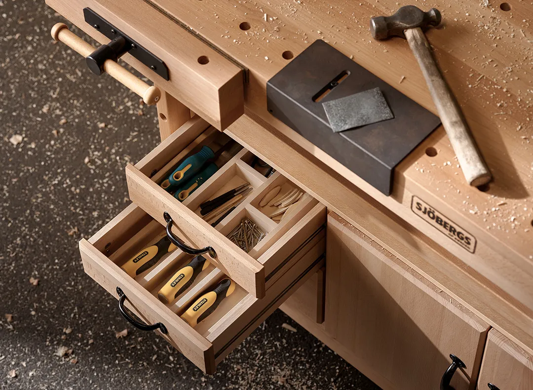 Arbetsbänk med olika verktyg och spikar i öppna lådor