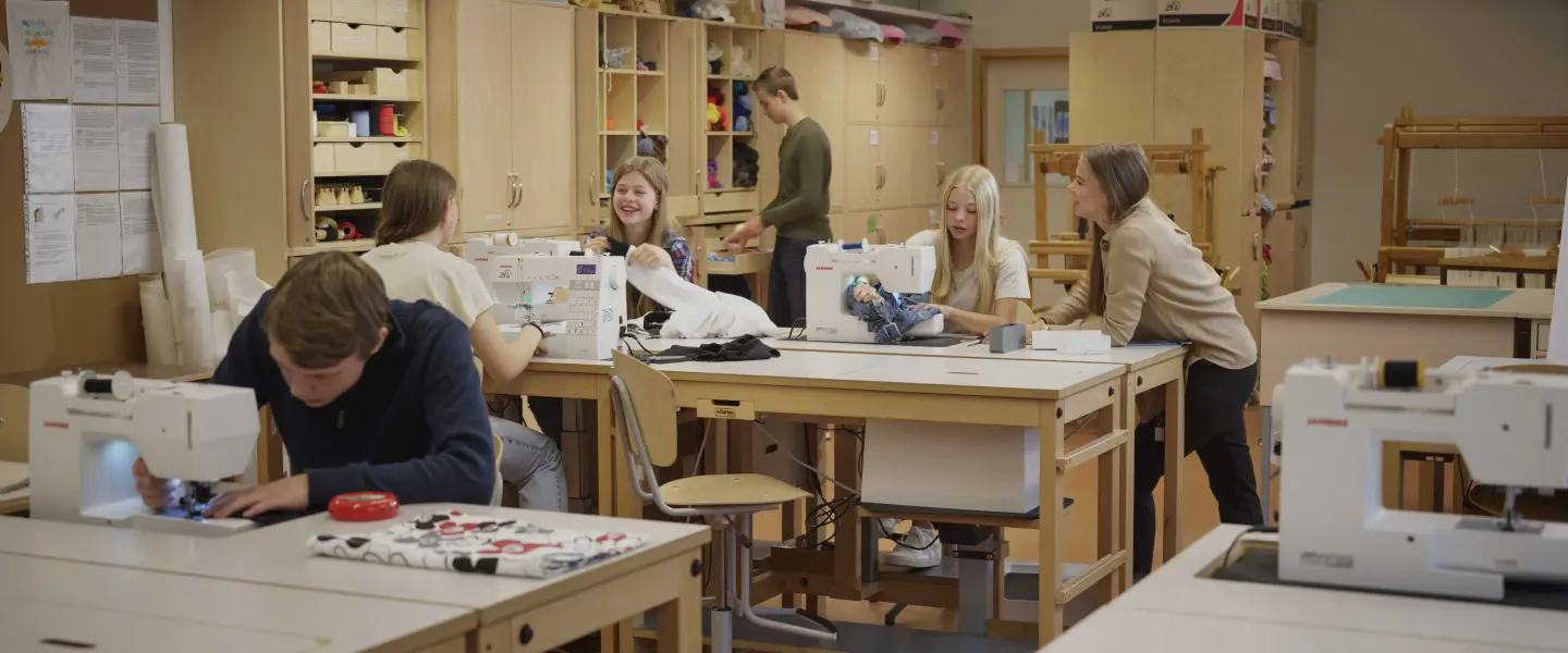Skolelever i en slöjdsal som använder symaskiner